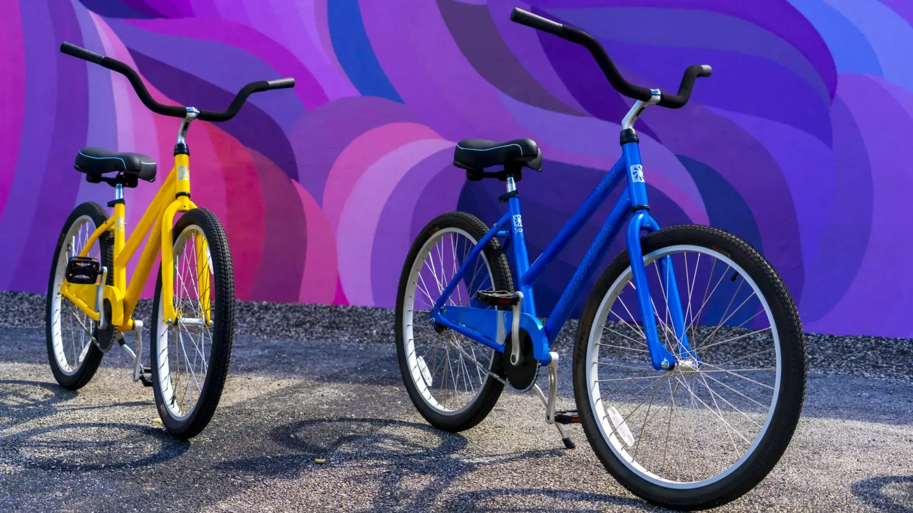Blue beach cruiser parked in front of a purple wave mural